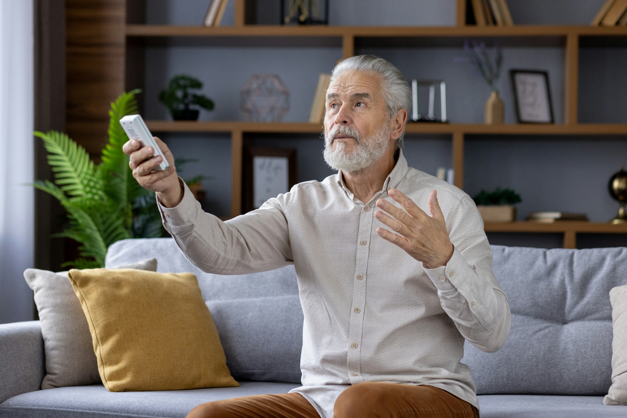 Senior man using remote control for air conditioning at home