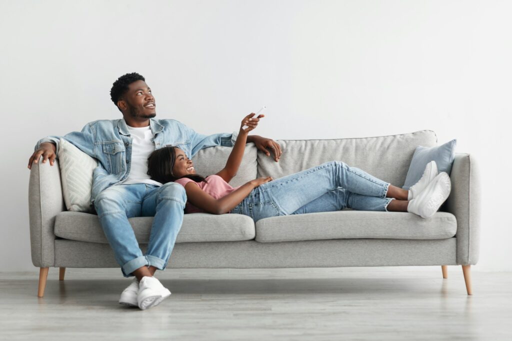 Young black woman switching on air conditioning at home